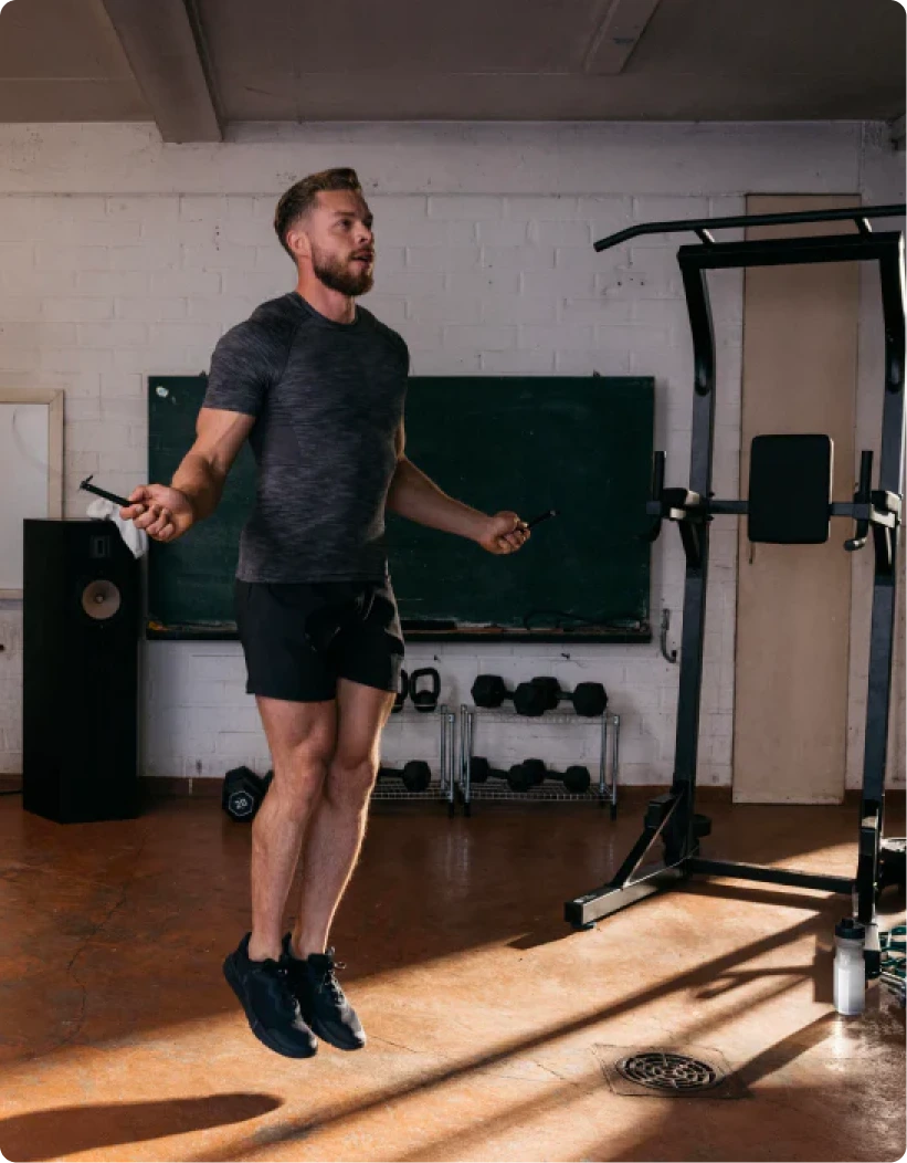 Man jumping mid-air on gym equipment, showcasing athleticism and high-performance fitness in a Decathlon.ae training environment emphasizing the brand's presence on the .ae domain, supported by Gatehills.